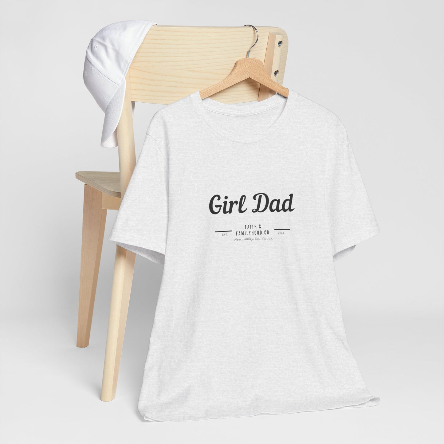 A close-up shot of a "Girl Dad" t-shirt hanging on a wooden hanger, showcasing the stylish design and comfortable fit of this Dad Shirts collection.